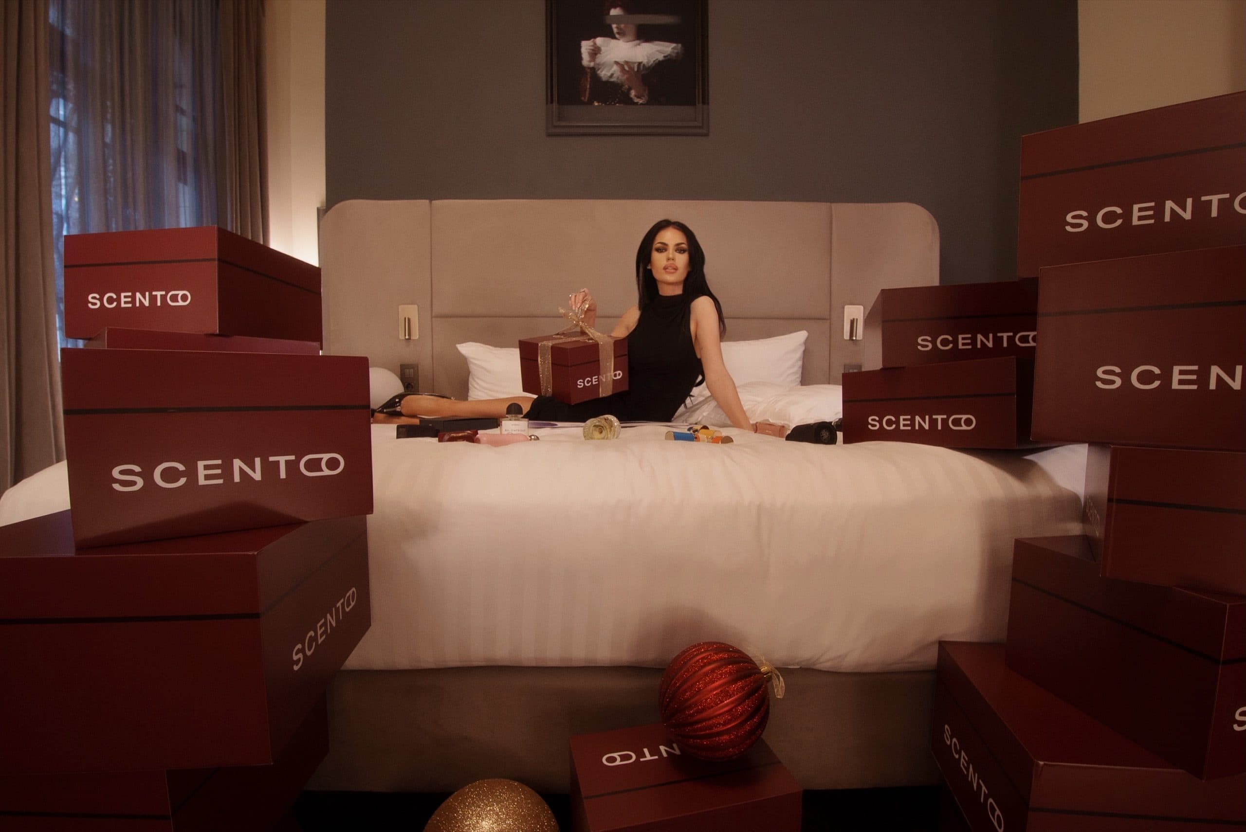 Scento-Geschenkboxen und ein Geschenk mit Schleife auf einem Hotelbett